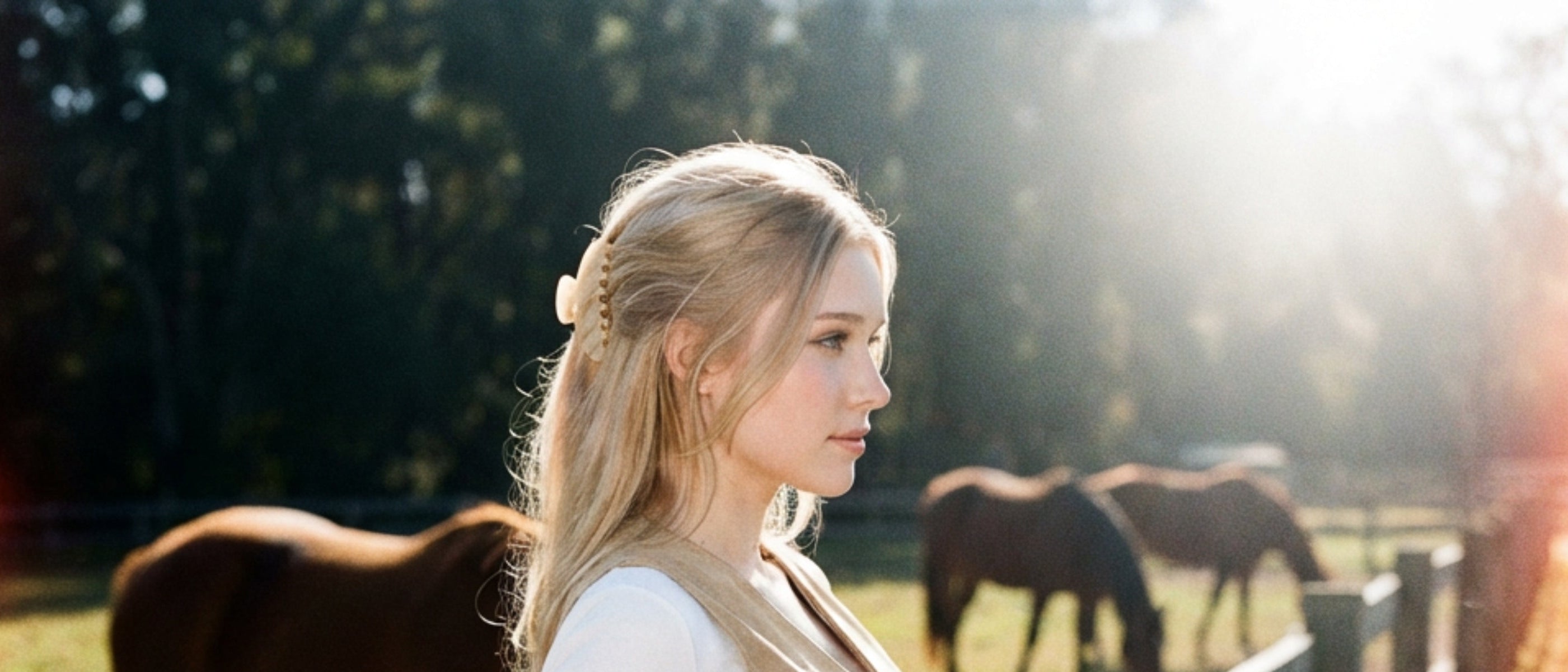 Woman sitting on a wooden fence with horses in the background showing off the medium cream swirl Lovebell Claw